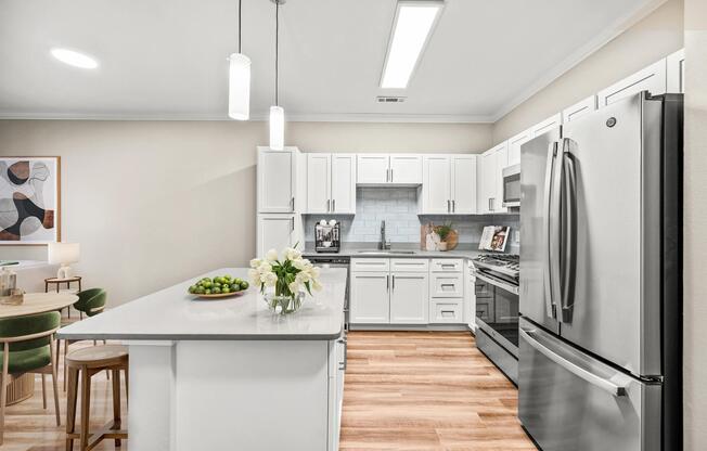 Bright kitchen with a generous island, white cabinetry, stainless steel appliances, and inviting finishes designed for everyday gathering and meal prep.