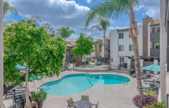 a swimming pool with tables and chairs and palm trees at City View Apartments at Warner Center, Woodland Hills, CA