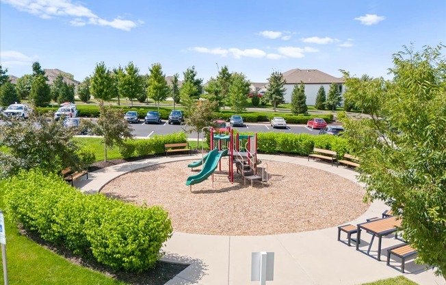 A playground with a green slide and a red swing set.