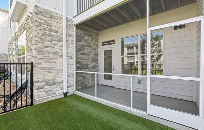 a patio with grass and a stone wall on the side of a house at Drift, Daytona Beach, FL, 32117