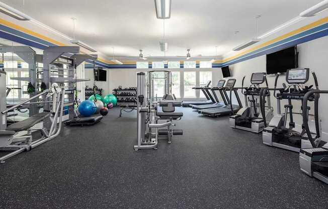 A spacious gym with various exercise equipment and a blue exercise ball.