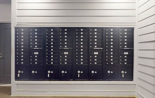 A row of black mailboxes are lined up on a wall.