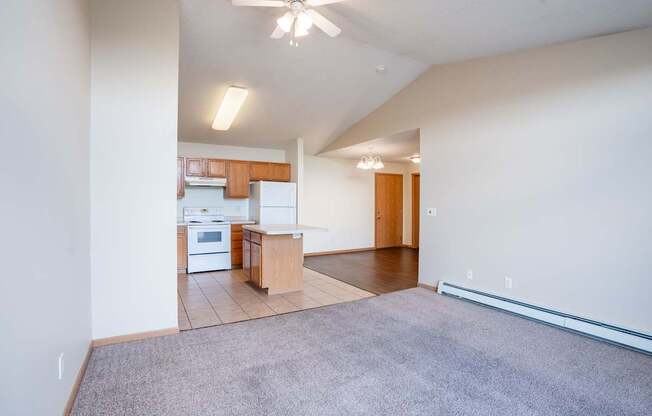 A spacious living room with a kitchen in the background. Bismarck, ND Sierra Ridge Apartments