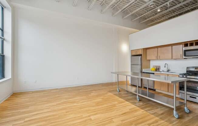 A kitchen area with a wooden floor and a white wall.