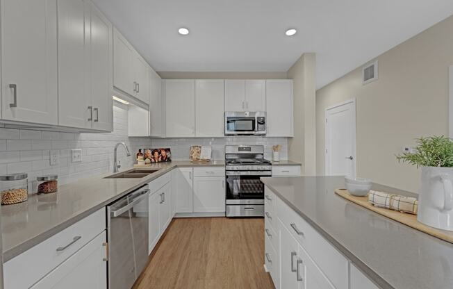 a large kitchen with white cabinets and stainless steel appliances