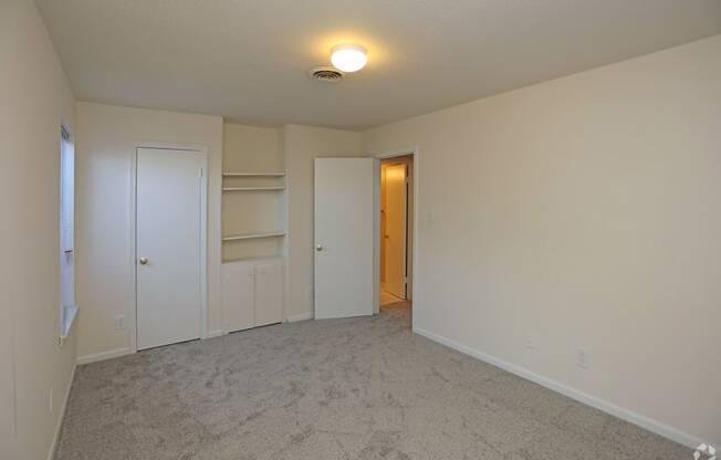 a empty living room with a closet and a door to a hallway