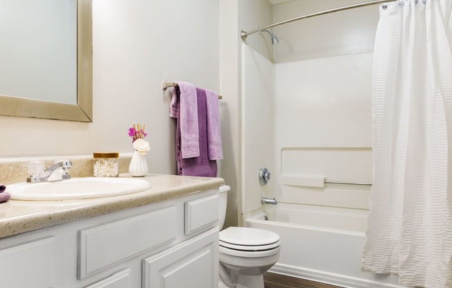 a bathroom with a white bathtub and a white sink with a purple towel