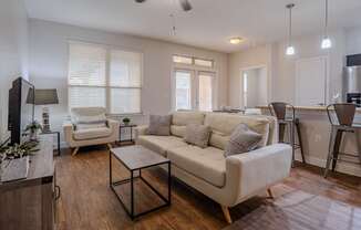 a living room with a couch and a chair in front of a dining room table