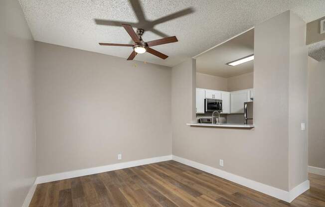 A room with a ceiling fan and wooden flooring.