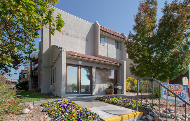 the front of a building with a staircase and flowers in front of it