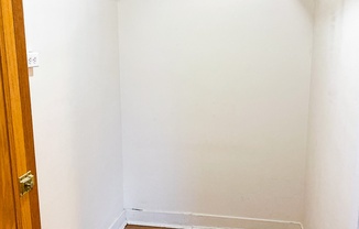 an empty closet with white walls and a wooden floor