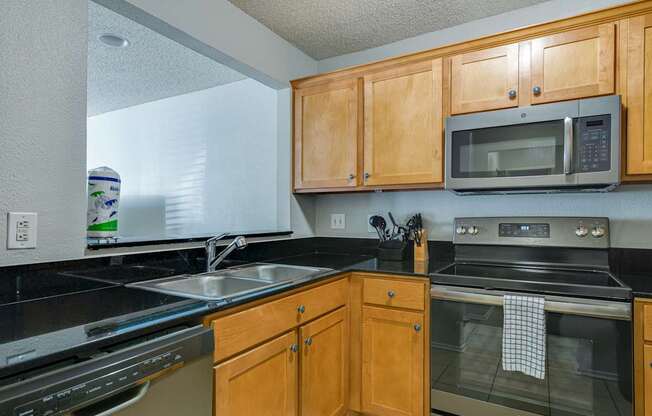 A kitchen with wooden cabinets and black countertops.