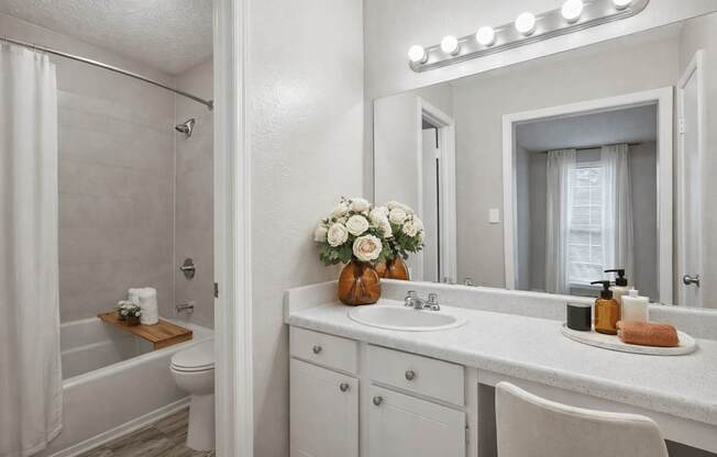 A white bathroom with a vanity, toilet, and a shower.