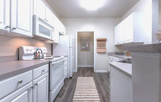 A kitchen with white cabinets and a grey counter top.