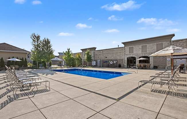 A large outdoor heated swimming pool surrounded by resort-style loungers and umbrellas at The Residences at Toscana Park in Granger, Indiana.