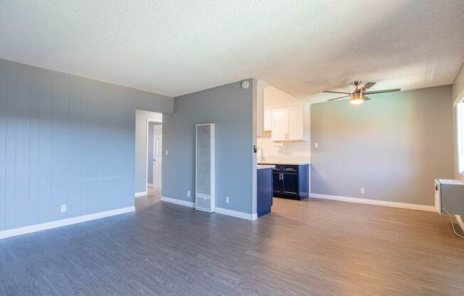 A spacious room with a ceiling fan and a kitchenette.