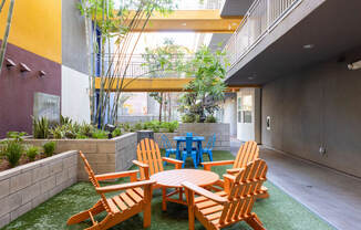 a courtyard with wooden chairs and tables and plants