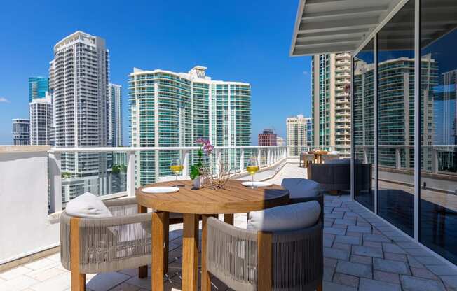 a patio with a table and chairs on a balcony overlooking the city