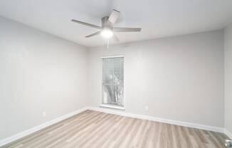 an empty room with a ceiling fan and a window
