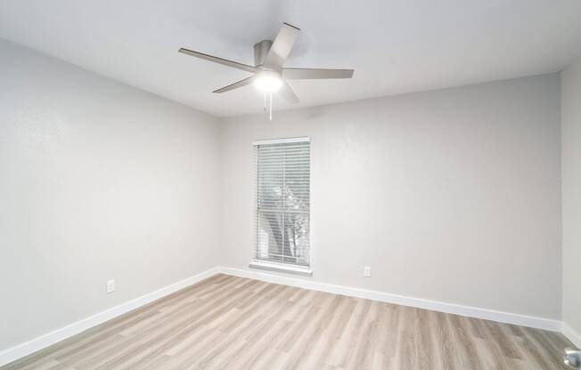 an empty room with a ceiling fan and a window