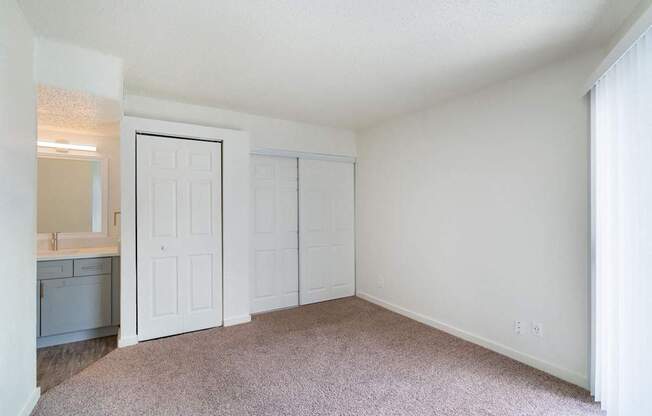 a bedroom with white walls and carpet and a door to a bathroom