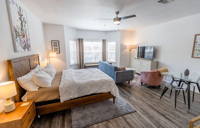 a bedroom with a bed and a couch in front of a tv
