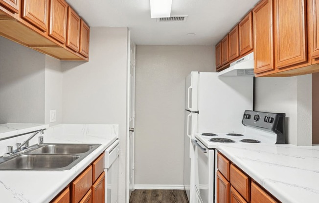 Unfurnished A4 floor plan kitchen with white appliances and wooden cabinets Noel on The Parkway in Dallas, TX