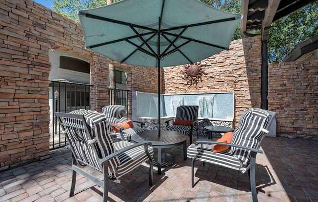 A patio with a table and chairs under an umbrella.