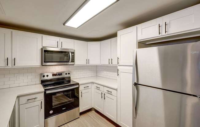 A kitchen with a stainless steel refrigerator, oven, and microwave.
