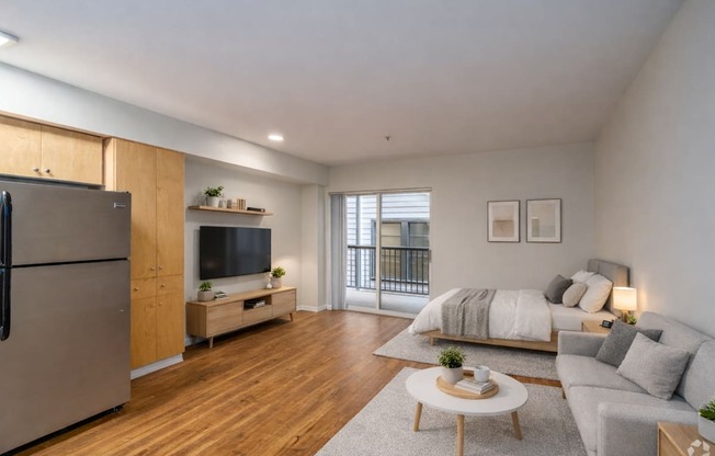 A modern living room with a flat screen TV, a sofa, a coffee table, and a refrigerator.