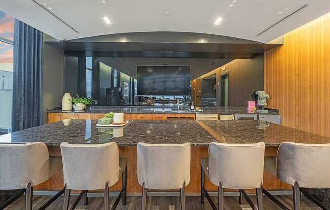 a large kitchen with marble counter tops and a long bar with chairs