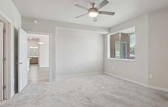 A spacious room with a ceiling fan and carpeted floor.