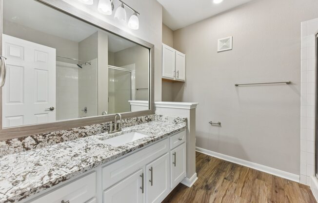 A bathroom with a marble countertop and white cabinets.