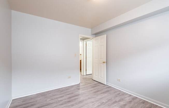 A room with a white door and grey flooring.