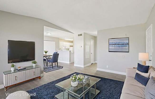 A living room with a television, a sofa, and a glass coffee table.
