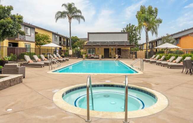 A large outdoor swimming pool surrounded by sun loungers and palm trees.