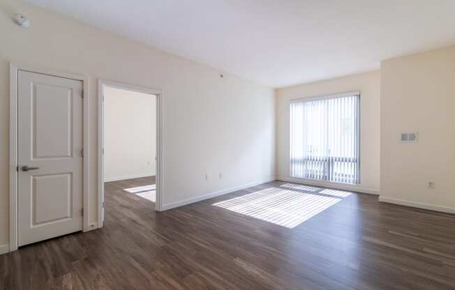 an empty living room with wood flooring and a window