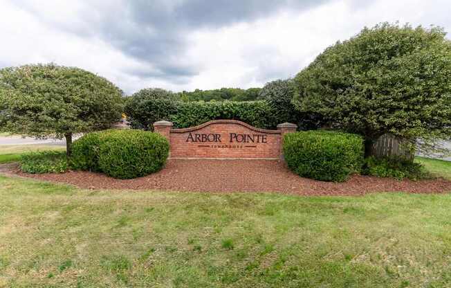 A sign that says Arbor Pointe is surrounded by bushes and trees.