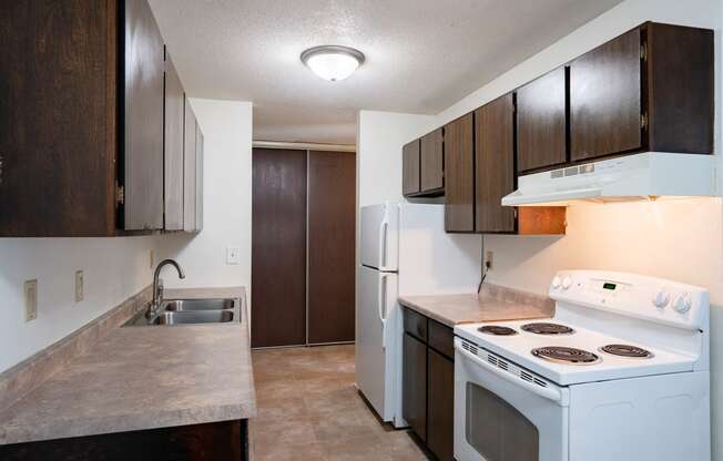 an empty kitchen with white appliances and wooden cabinets. Coon Rapids, MN Robinwood Apartments