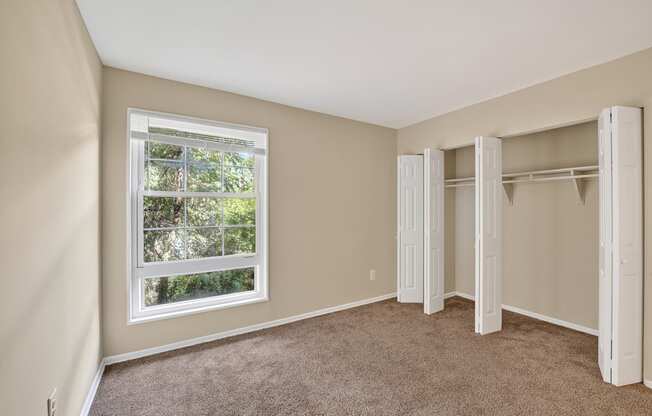 A room with a window and a carpeted floor.