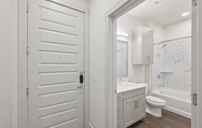 A white bathroom with a toilet, sink, and bathtub.