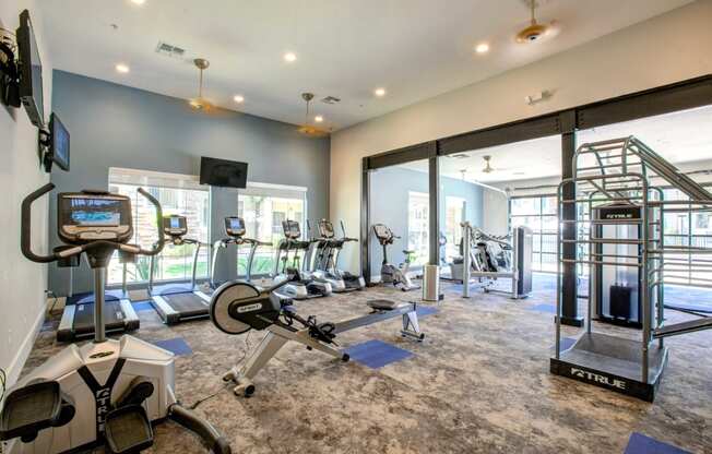 North Phoenix AZ Apartments - Expansive Fitness Center Featuring Various Cardio Equipment, Ceiling Fans, and TVs