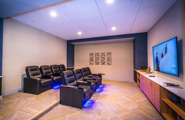 A private movie theater room with tiered comfortable leather chairs and large screen at Lofts at South Lake at Lofts at South Lake, Clermont, FL, 34711