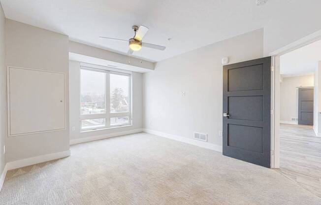 A room with a ceiling fan and a large window.
