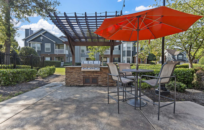 a patio with an umbrella and tables with chairs and a grill