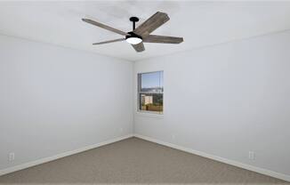 an empty room with a ceiling fan and a window