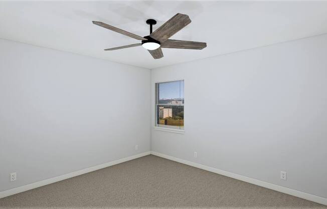 an empty room with a ceiling fan and a window