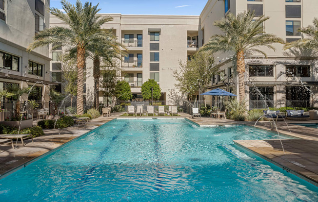 a swimming pool with palm trees and a building in the background