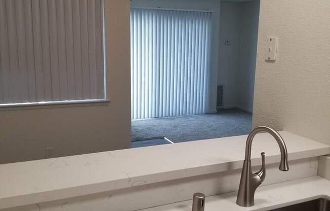 A kitchen with a stainless steel sink and a white countertop.