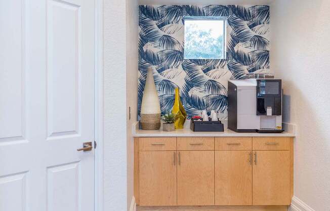 A white door is on the left of a wooden cabinet with a coffee maker on top.